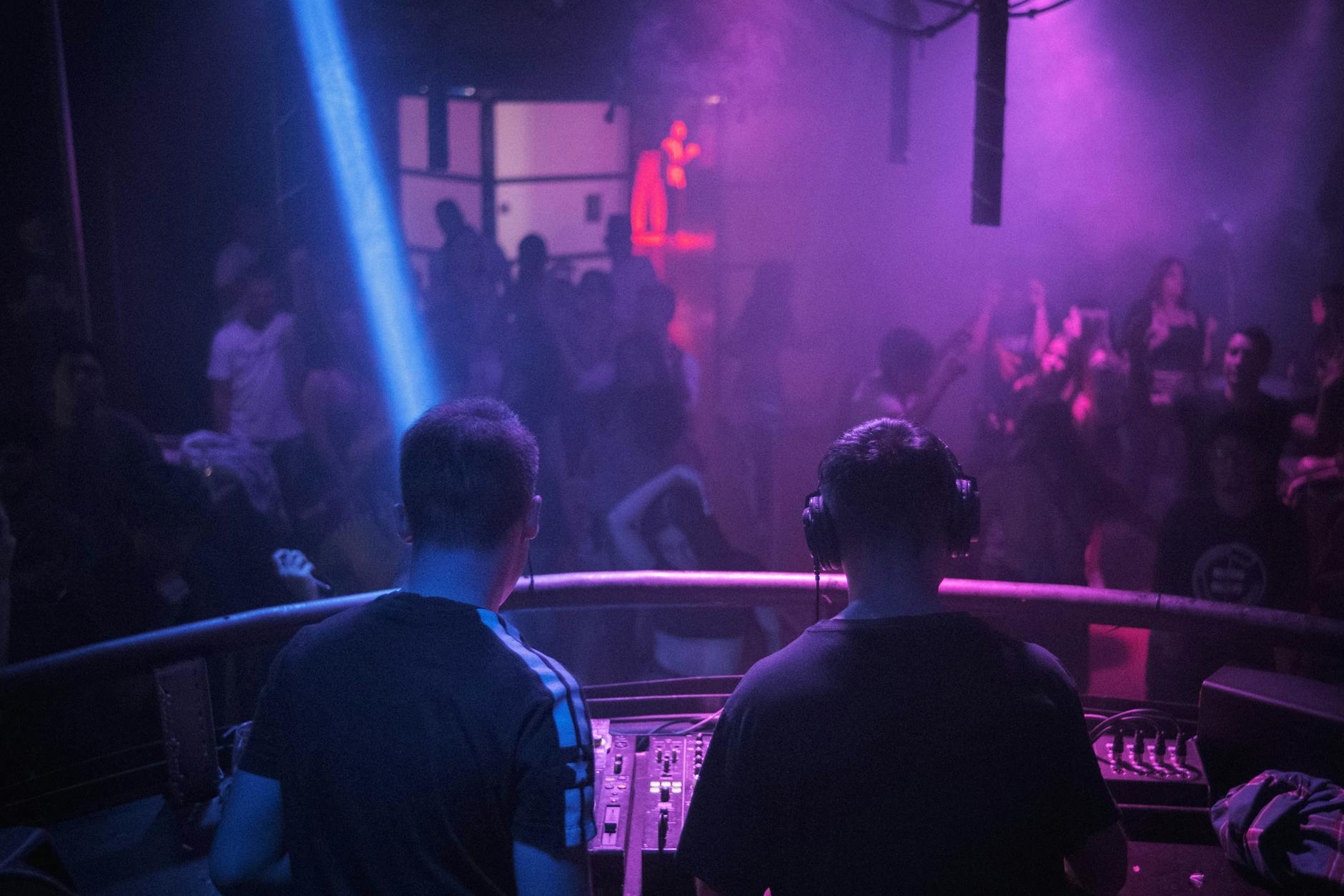 Nightclub dance floor with colourful lights and DJ performing