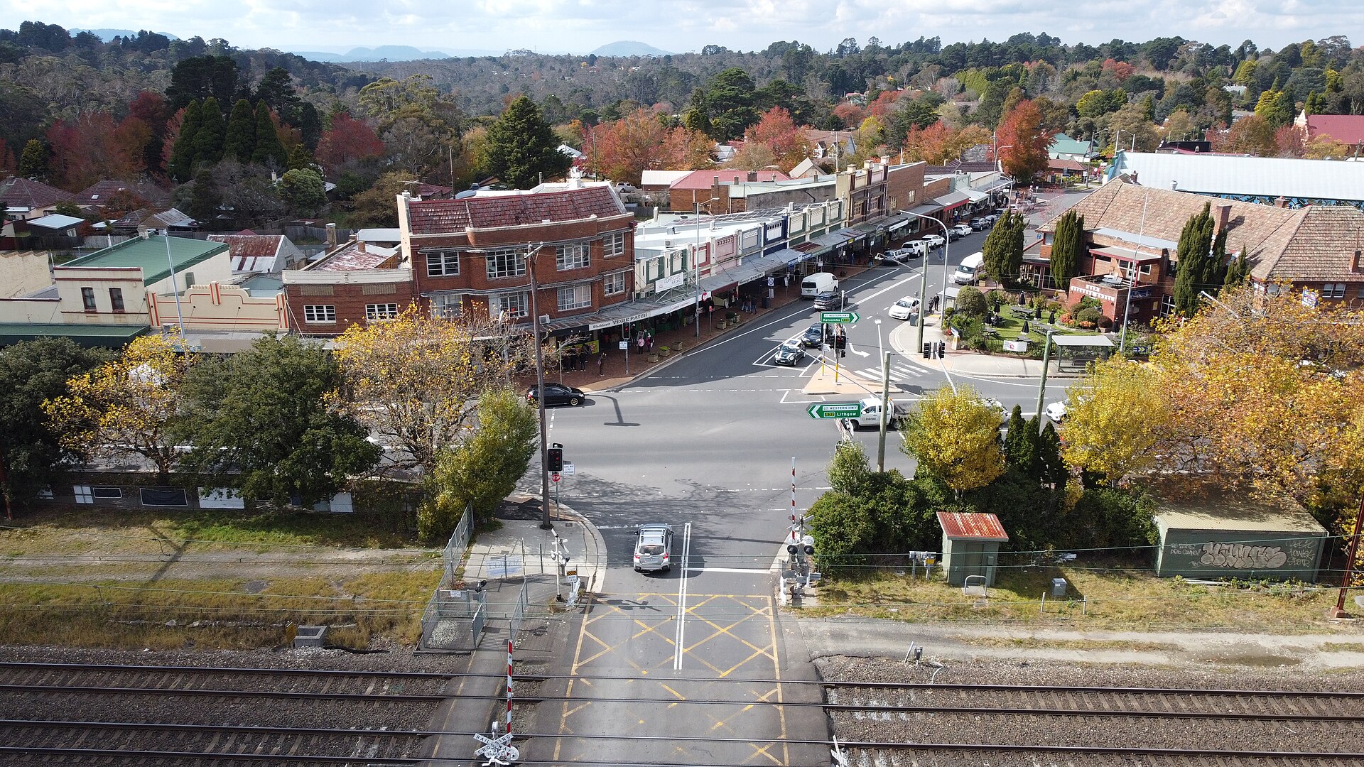 Aerial view of Blackheath's main street and railway crossing surrounded by red and gold autumn trees