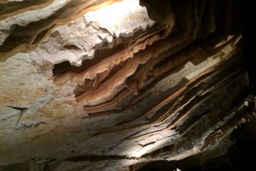Layered limestone flowstone formations lit inside a chamber at Jenolan Caves